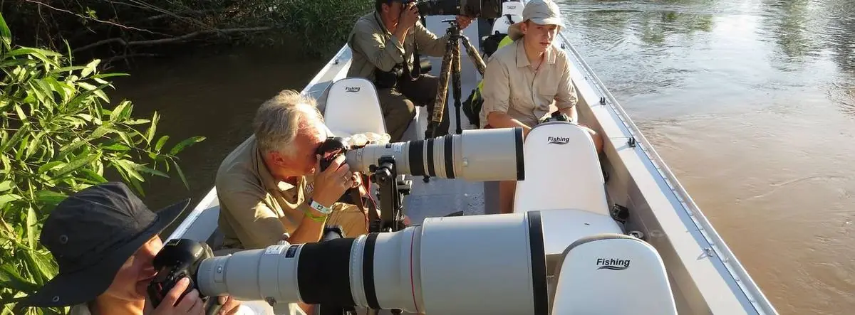 Photographers with long lenses in a small boat on the river